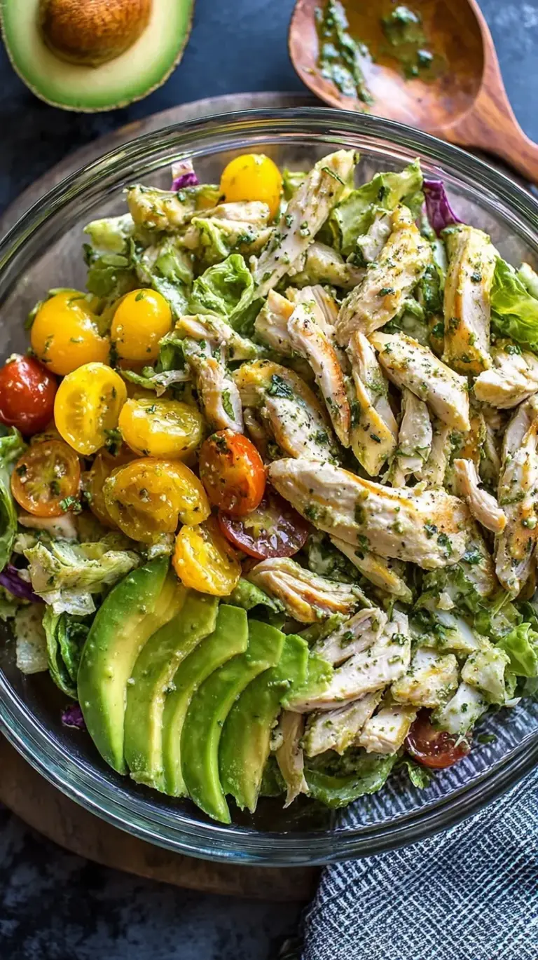 A bowl of creamy avocado chicken salad with fresh cilantro and red onions