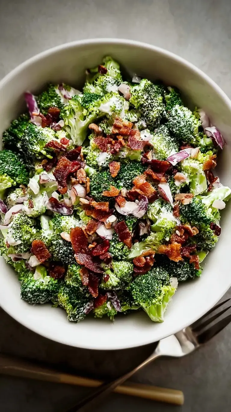A vibrant bowl of creamy broccoli salad with red onion, bacon, cranberries, and sunflower seeds, ready to serve.