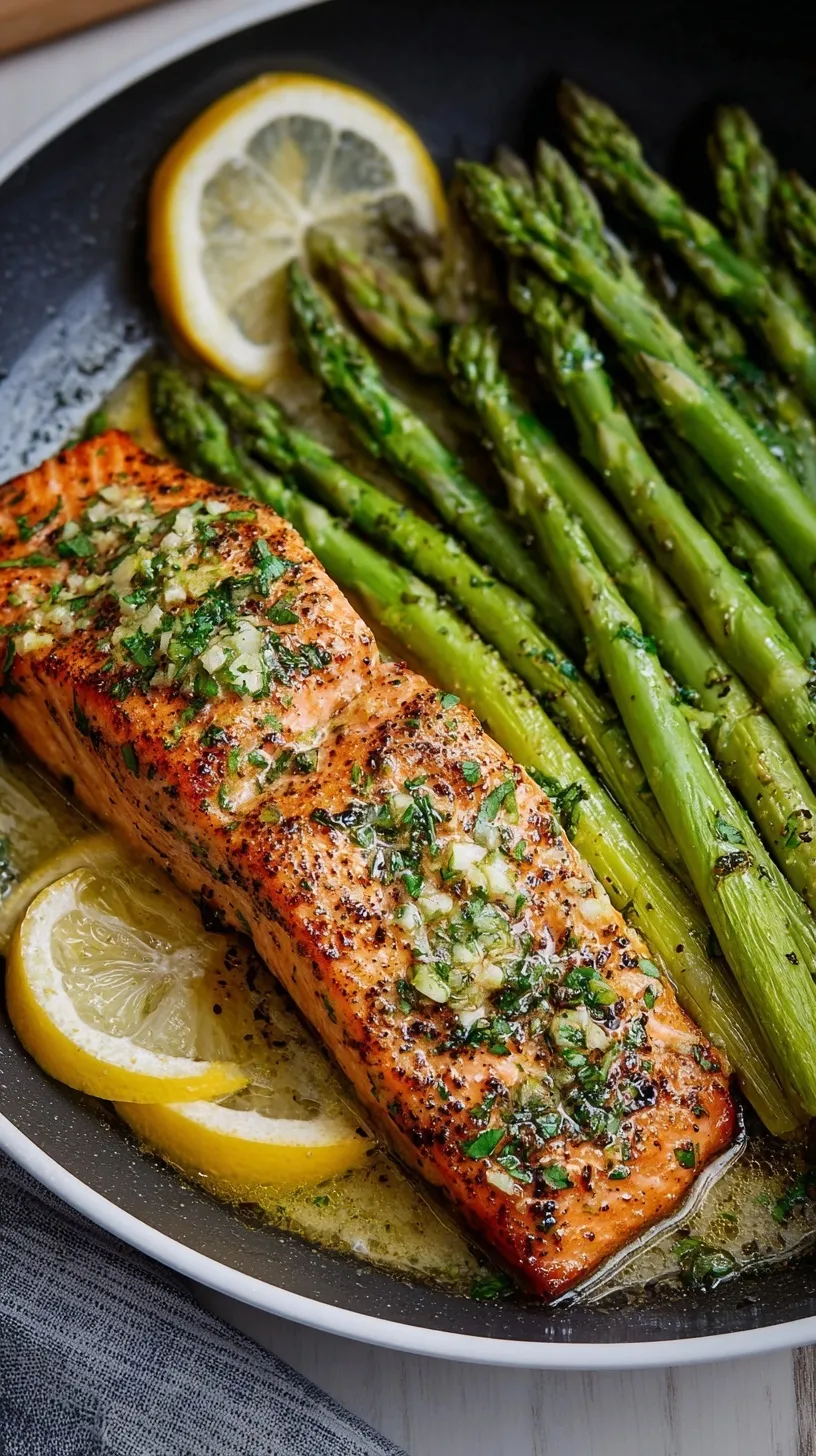 Pan-seared salmon fillets with tender asparagus and garlic butter in a skillet.