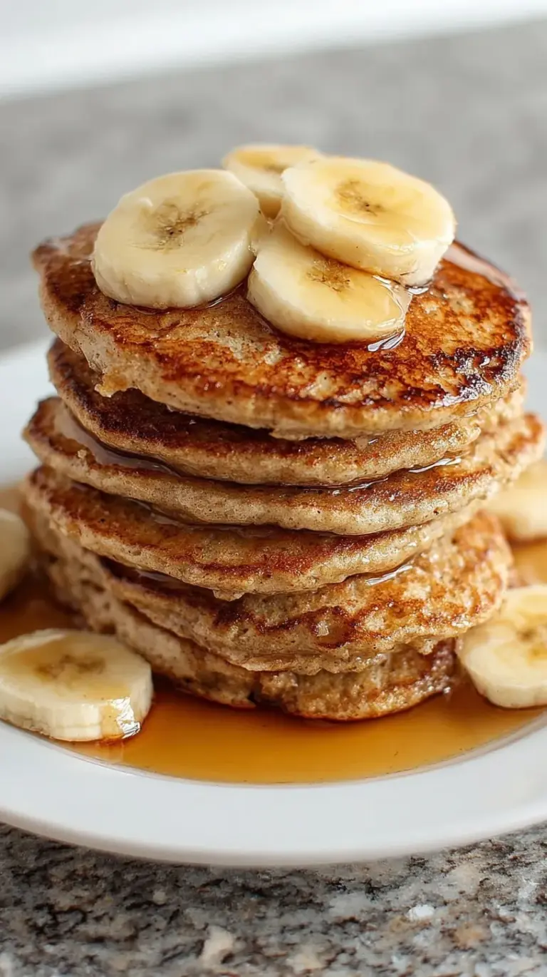 A stack of golden brown whole wheat banana pancakes topped with fresh fruit and honey