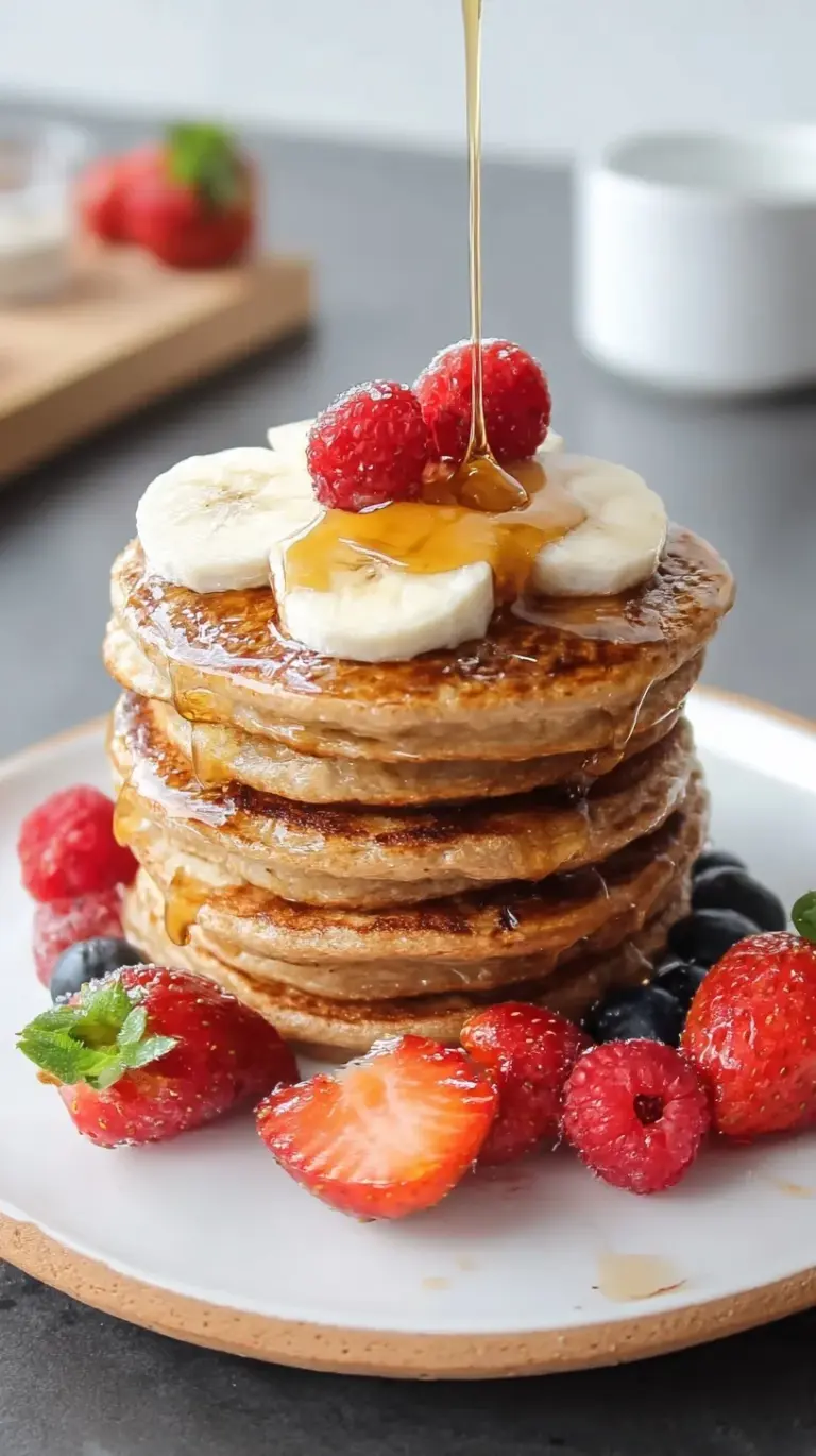 A stack of golden brown healthy protein pancakes topped with fresh fruit.